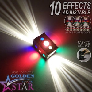 May include: A black cube-shaped wall sconce with 10 adjustable light effects. The sconce has four colored lights: red, green, blue, and white. The text "10 EFFECTS ADJUSTABLE" is in the upper right corner of the image. The text "IN THE SAME SCONCE" is below the light effects. The text "EASY TO ADJUST" is in the lower right corner of the image. The text "WALL SCONCE GOLDEN COLORS STAR" is in the lower left corner of the image.