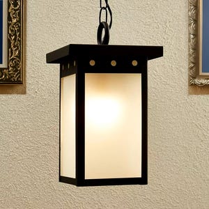 Puede incluir: Una lámpara colgante de metal negro con una pantalla de vidrio esmerilado. La luz cuelga de una cadena.