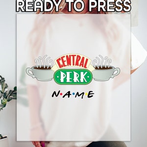 May include: White t-shirt with a green, red, and yellow "Central Perk" logo with two coffee cups and steam. The text "N.A.M.E" is below the logo.