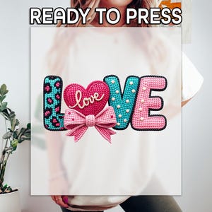 May include: A colorful graphic design featuring the word "LOVE" in a playful, textured style. The "L" has a teal leopard print, the "O" is a pink heart with "love" in cursive, the "V" is teal with white dots, and the "E" is pink. A pink bow is below the heart. The text "READY TO PRESS" is at the top.