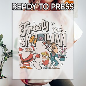 May include: A white graphic featuring the text "Frosty the Snowman" with cartoon illustrations of Frosty, Santa Claus, and other characters. The words "READY TO PRESS" are at the top.