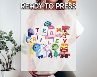 May include: A white graphic featuring the text "READY TO PRESS" at the top. Below, the image displays the words "TEAM RILEY" with colorful cartoon characters from the movie Inside Out. The characters are arranged around the letters.