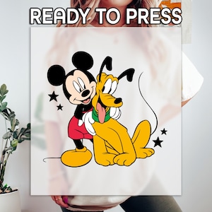 May include: A white graphic featuring Mickey Mouse hugging Pluto, with black stars scattered around them. Mickey Mouse wears red shorts, black gloves, and yellow shoes. Pluto is yellow with a green collar and a long, pink tongue. The text "READY TO PRESS" is at the top.