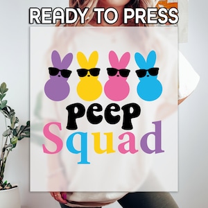 May include: White t-shirt with a graphic of four colorful cartoon peeps wearing sunglasses and the text "Peep Squad".