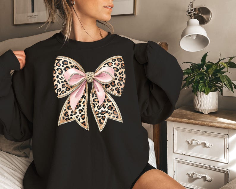 May include: Black sweatshirt with a large pink and brown leopard print bow with rhinestones on the front.