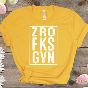 May include: Yellow t-shirt with a white box containing the text "ZRO FKS GVN".