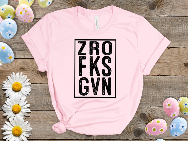 May include: Pink t-shirt with a black square graphic that says "ZRO FKS GVN".