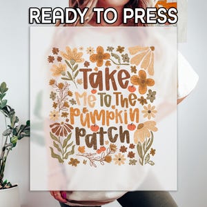 May include: A white t-shirt with a fall-themed graphic that says "Take Me To The Pumpkin Patch." The design includes floral elements and pumpkins in shades of brown, orange, and beige. The words "READY TO PRESS" are at the top.