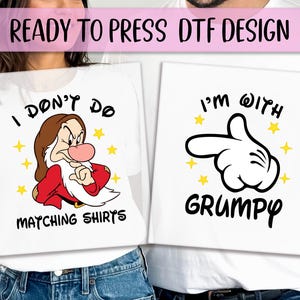 May include: White t-shirts with matching designs. One shirt features Grumpy from Snow White with the text "I don't do matching shirts". The other shirt has a Mickey Mouse hand with the text "I'm with Grumpy".