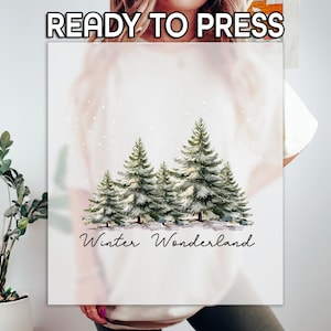 May include: A white graphic featuring a watercolor illustration of evergreen trees with snow falling. The text "Winter Wonderland" is written in a script font below the trees. The words "READY TO PRESS" are at the top.