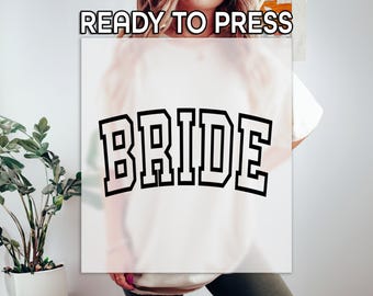 May include: White t-shirt with the word "BRIDE" printed in black block letters.