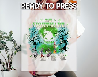 May include: White t-shirt featuring a colorful graphic from "The Nightmare Before Christmas." The design includes characters like Jack Skellington, Sally, and others crossing a street, with the words "The Nightmare" above. The phrase "READY TO PRESS" is at the top.