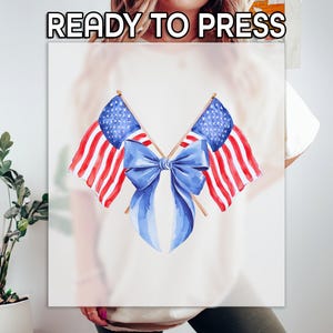 Puede incluir: Un dise&ntilde;o gr&aacute;fico blanco con dos banderas americanas de acuarela y un lazo azul en el centro. Las banderas tienen rayas rojas y blancas y campos de estrellas azules. El texto "READY TO PRESS" est&aacute; en la parte superior.