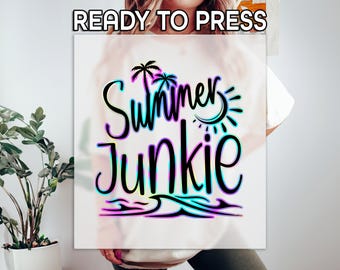 Könnte beinhalten: Ein weißes Grafikdesign mit dem Schriftzug "Summer Junkie" in einer farbenfrohen Schriftart. Das Design beinhaltet Palmen, eine Sonne und Wellen, mit dem Text "READY TO PRESS" oben. Ideal für Sommerbekleidung.