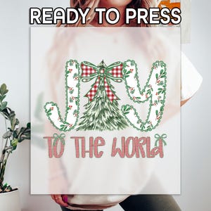 May include: A white graphic featuring the words "JOY TO THE WORLD" in a festive design. The word "JOY" is in a decorative font with green and red accents. A Christmas tree and bow are in the center.