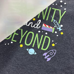 May include: Dark gray t-shirt with the phrase "Infinity and Beyond" in green and white, with space-themed graphics. The design includes a rocket, planet, stars, and a syringe.