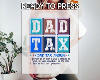 May include: A white graphic tee with the words "READY TO PRESS" at the top. The design features the words "DAD TAX" in a grid of colorful boxes. Below, the text defines "DAD TAX" as a noun, with two humorous points.