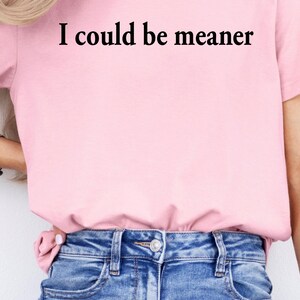 Puede incluir: Una camiseta rosa con el texto "I could be meaner" impreso en negro.