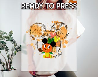 Könnte beinhalten: Weißes T-Shirt mit einer Grafik mit Mickey Mouse Ohren, orangefarbenen Spritzern und einer Orange Bird-Figur, die Luftballons hält. Der Text "READY TO PRESS" steht oben und "Orange Bird" steht unten.