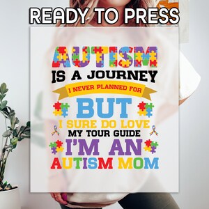 May include: White t-shirt with a colorful graphic that reads "Autism is a journey I never planned for but I sure do love my tour guide I'm an Autism Mom".