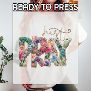 May include: A white canvas with the words "READY TO PRESS" at the top. The words "just PRAY" are displayed in a floral design with various colors, including pink, blue, and green. The word "just" is in a cursive font.