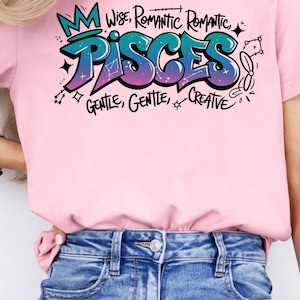 K&ouml;nnte beinhalten: Rosafarbenes T-Shirt mit einem farbenfrohen Grafikdesign mit dem Wort "PISCES" im Graffiti-Stil, zusammen mit den Worten "Wise, Romantic, Gentle, Creative". Das Shirt wird mit blauen Jeans kombiniert.