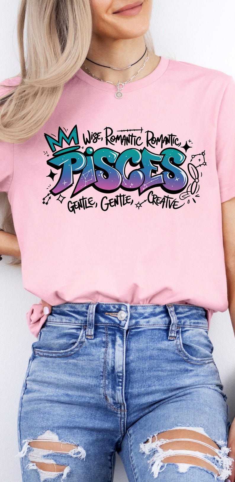 K&ouml;nnte beinhalten: Rosafarbenes T-Shirt mit einem farbenfrohen Grafikdesign mit dem Wort "PISCES" im Graffiti-Stil, zusammen mit den Worten "Wise, Romantic, Gentle, Creative". Das Shirt wird mit blauen Jeans kombiniert.