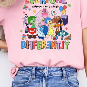 May include: Pink t-shirt with a graphic of characters from the movie Inside Out. The text on the shirt reads "Everyone communicates differently".