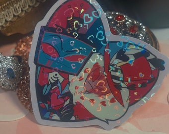 May include: A heart-shaped sticker featuring two cartoon characters embracing. The sticker has a holographic effect with red, blue, and white colors. The design includes hearts and other decorative elements, creating a vibrant and eye-catching aesthetic.