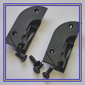 Op de afbeelding: Twee donkergrijze kunststof componenten met gebogen randen en cirkelvormige gaten, samen met verschillende kleine zwarte bevestigingsmiddelen. De componenten hebben een mechanisch ontwerp, wat suggereert dat ze deel uitmaken van een grotere assemblage. De onderdelen liggen op een witte ondergrond.