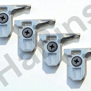 Op de afbeelding: Vier zilverkleurige kastscharnieren met een schroef in het midden. Elk scharnier heeft een rechthoekige basis en een gebogen arm. Ze zijn geplaatst op een witte achtergrond. De scharnieren zijn van metaal.