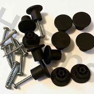 Może przedstawiać: Zestaw czarnych gałek do szafek i śrub. Gałki mają okrągły, płaski wierzch i cylindryczną podstawę. Śruby są srebrne i mają spiczastą końcówkę. Sprzęt jest prawdopodobnie przeznaczony do mebli lub szafek.