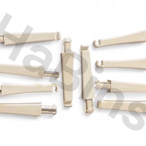 Op de afbeelding: Een verzameling beige plastic tuimelschakelaars, elk met een rechthoekig lichaam en een haak of lus aan één uiteinde. Sommige tuimelschakelaars hebben een afgerond uiteinde, andere een plat uiteinde. De tuimelschakelaars zijn gerangschikt op een witte achtergrond.