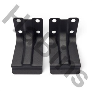 May include: Two identical matte black metal L-shaped brackets, each featuring a vertical section with two circular mounting holes and a flat horizontal base. The brackets have a smooth, uniform finish and a sturdy, angular construction for mounting.