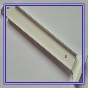 Op de afbeelding: Een witte metalen plankdrager met een rechthoekige vorm en een reeks kleine gaten langs de bovenrand. De beugel heeft een haakse buiging aan één uiteinde en een enkel rond gat.