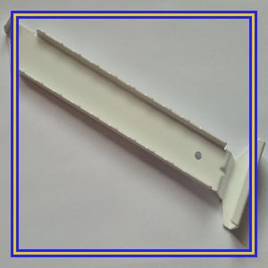 Op de afbeelding: Een witte metalen plankbeugel met een reeks gelijkmatig verdeelde inkepingen over de lengte. De beugel heeft een haakse hoek voor montage en een klein gat. Het item is ontworpen voor het ondersteunen van planken.