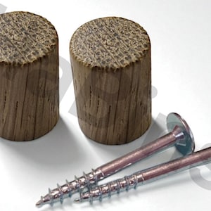 Könnte beinhalten: Zwei Holzdübel und zwei silberne Schrauben mit flachen Köpfen werden auf einer weißen Oberfläche gezeigt. Die Dübel sind zylindrisch, mit einer strukturierten, hellbraunen Oberfläche. Die Schrauben haben einen Gewindeschaft und einen breiten, flachen Kopf.