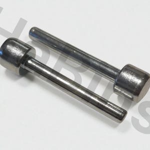 Op de afbeelding: Twee roestvrijstalen metalen gereedschappen met cilindrische handvatten en afgeronde koppen. De gereedschappen zijn verschillend van grootte, waarbij de ene korter is dan de andere. De gereedschappen staan op een witte achtergrond.