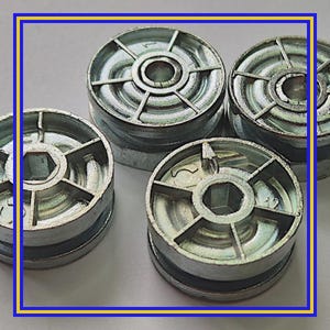 May include: Four silver metal spools are shown in a close-up view. Each spool has a circular design with radial spokes and a central hexagonal opening. The spools are stacked and appear to be new.