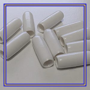 Op de afbeelding: Een verzameling witte, cilindervormige objecten met afgeronde uiteinden en open holtes. De objecten zijn verspreid over een lichtgekleurd oppervlak. De algehele esthetiek is schoon en minimalistisch.