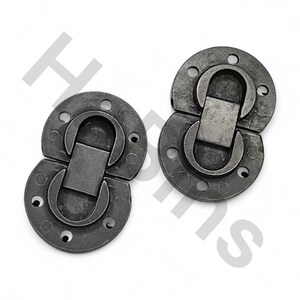 Pode incluir: Uma caneca de cerâmica branca com uma alça preta e o texto "But First, Coffee" em preto, com uma fonte manuscrita. A caneca está sobre uma superfície branca.