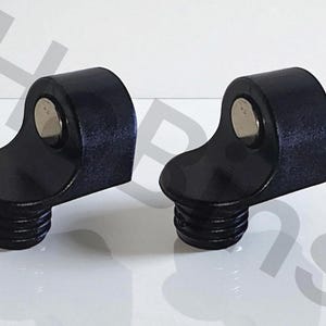 May include: Two black, angled cabinet knobs with a textured finish and a silver-colored inset. The knobs have a threaded base for easy installation. The design is modern and minimalist, suitable for various furniture styles.