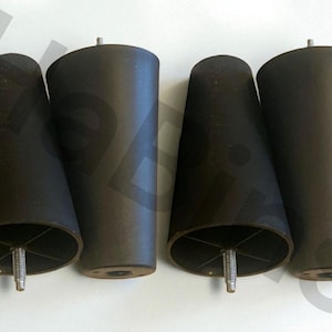 May include: Four black, tapered furniture legs. Each leg has a cylindrical shape with a threaded bolt for attachment. The legs are made of a dark, matte material and are designed to support furniture.