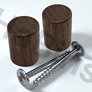 May include: Two cylindrical wooden furniture knobs with a dark brown finish, alongside two silver screws. The knobs are made of wood and have a smooth, rounded top. The screws have a flat head and a threaded shaft.