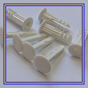 May include: A collection of off-white plastic wall anchors. Each anchor has a cylindrical body with a ridged design and a flat, circular head. The anchors are designed to expand when a screw is inserted, providing a secure hold in drywall or other materials.