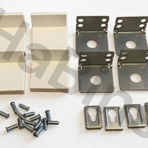 Op de afbeelding: Een hardwarekit met diverse metalen componenten. De kit bevat zes beige L-vormige beugels, zes scharnierende metalen beugels met schroefgaten, vier sleutelgatvormige metalen platen en een verzameling zilveren schroeven.