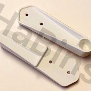 Op de afbeelding: Twee witte kunststof componenten met een rechthoekige vorm en afgeronde randen. Elk stuk heeft twee of drie kleine gaten en een cirkelvormige inkeping. De items lijken nieuw te zijn.