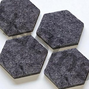Puede incluir: Cuatro posavasos hexagonales de fieltro gris oscuro dispuestos sobre una superficie blanca. Los posavasos tienen un aspecto texturizado y un diseño sencillo y moderno. Ideales para proteger superficies.