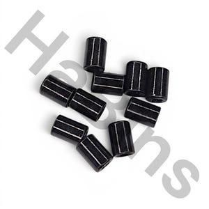 May include: A collection of seven small, cylindrical, black beads with a smooth, glossy finish. Each bead features a hollow center and a uniform, tubular shape. The beads are arranged in a loose cluster, showcasing their dark, reflective surface.