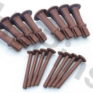 Può includere: Una collezione di tasselli e viti da muro in plastica marrone. I tasselli hanno una testa larga e piatta e un corpo scanalato. Le viti sono lunghe e cilindriche con una testa piatta.